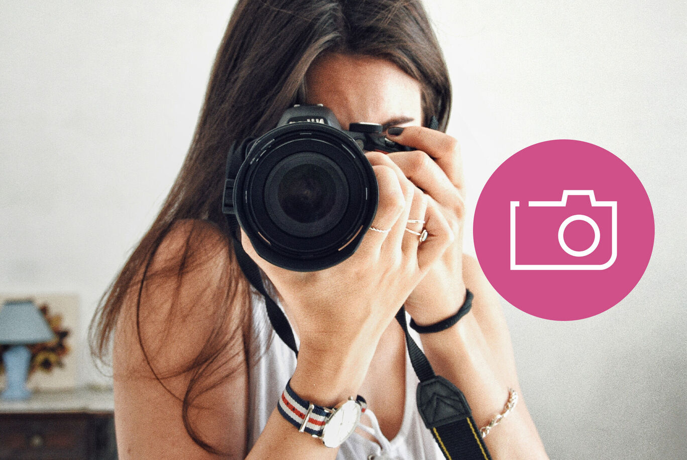 Osoba drží fotoaparát a fotografuje. V pozadí sú jednoduchý nábytok.