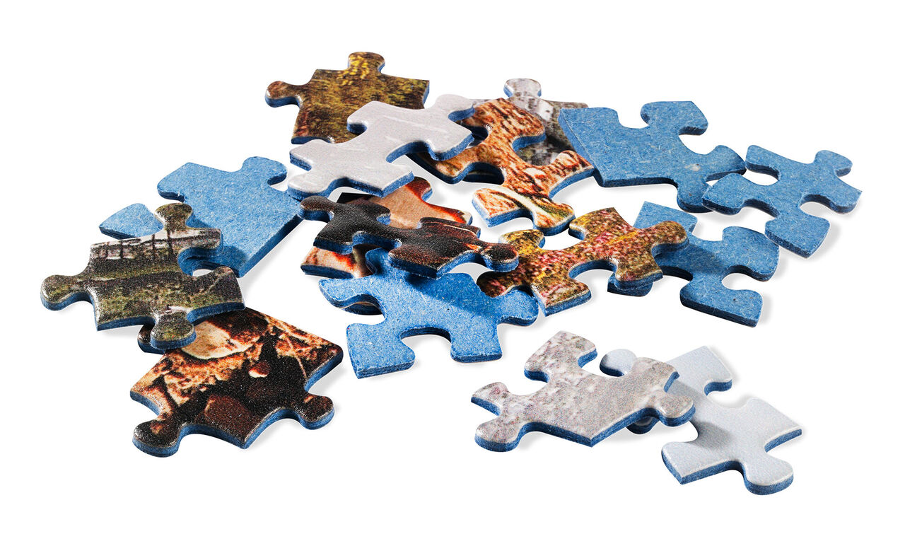 Farebné dieliky puzzle rozsypané na stole.