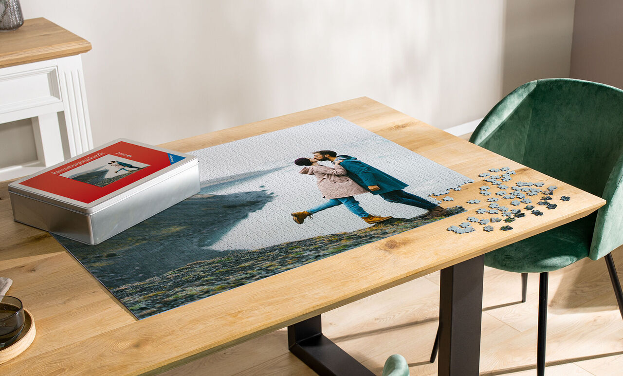 Pár na veľkej fotopuzzle na drevenom stole v objatí.