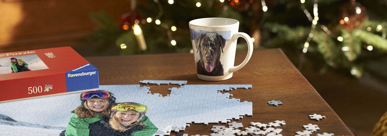 Starostlivo vyrobené puzzle a personalizovaná šálka stoja na stole, obklopené vianočnými svetlami.