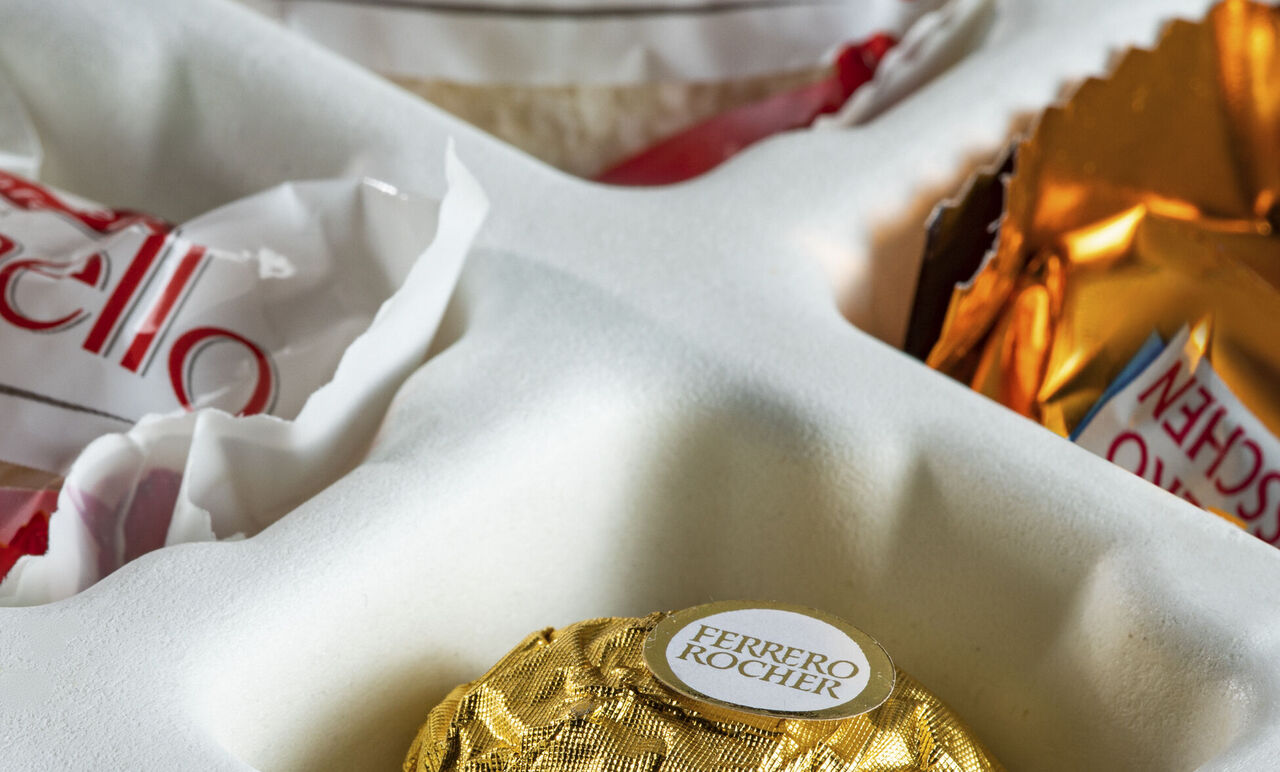 Radostný výber praliniek, vrátane Ferrero Rocher v zlatej fólii a ďalších sladkostí, ktoré potešia pri darovaní.