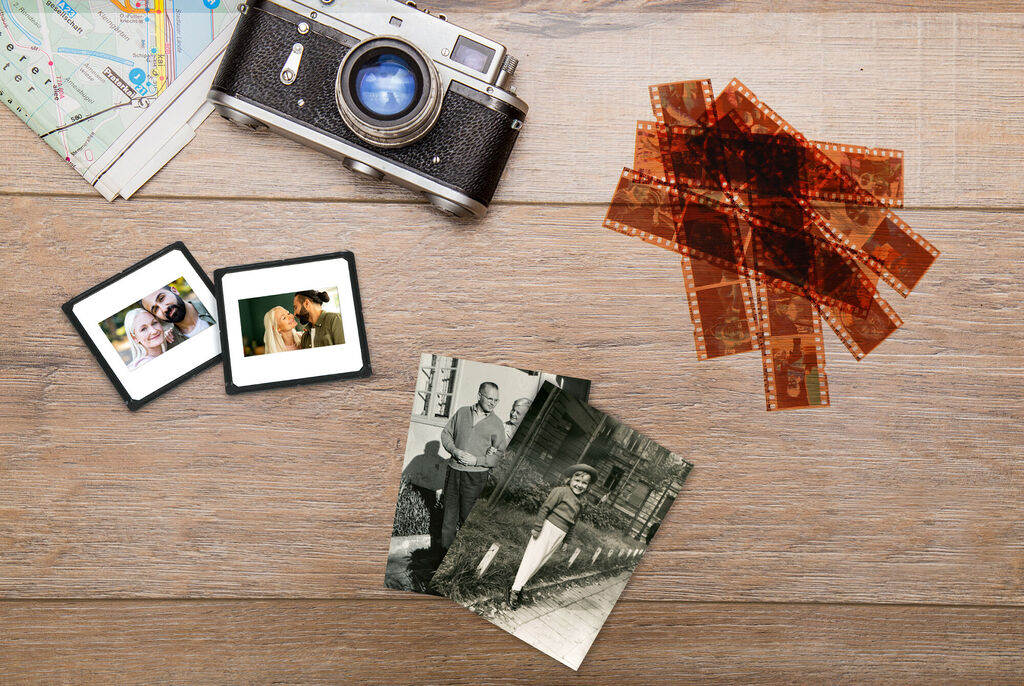 Fotoaparát, staré fotografie, negatívy a mapy na drevenom stole.