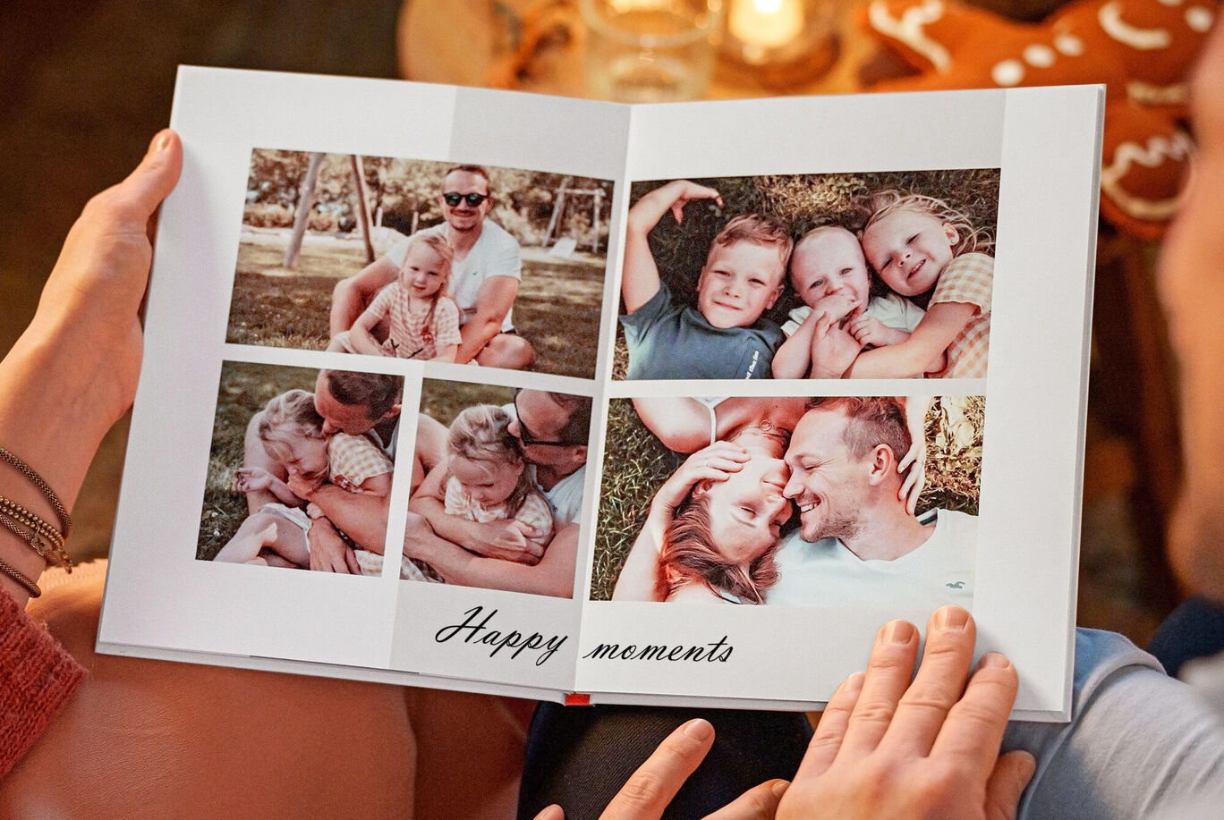 Otvorená CEWE FOTOKNIHA so šťastnými momentmi v obrazoch, držaná dvoma osobami.