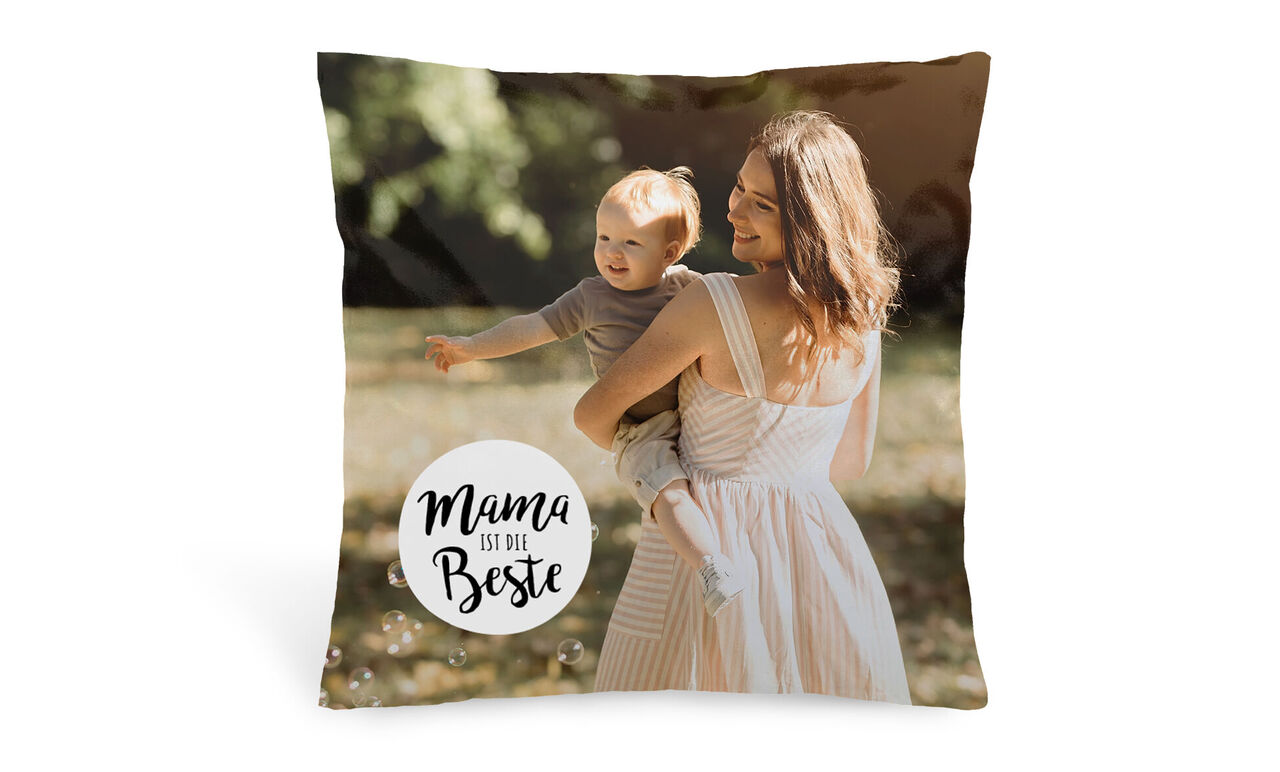 Milujúca mama nesie dieťa v prírode. Veselá atmosféra s bublinami. Vankúš s nápisom 'Mama je najlepšia'.