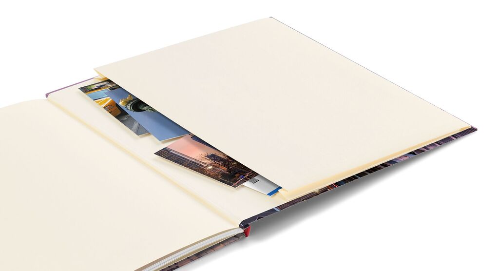 Otvorená fotokniha s prázdnymi stránkami a vloženými fotografiami.