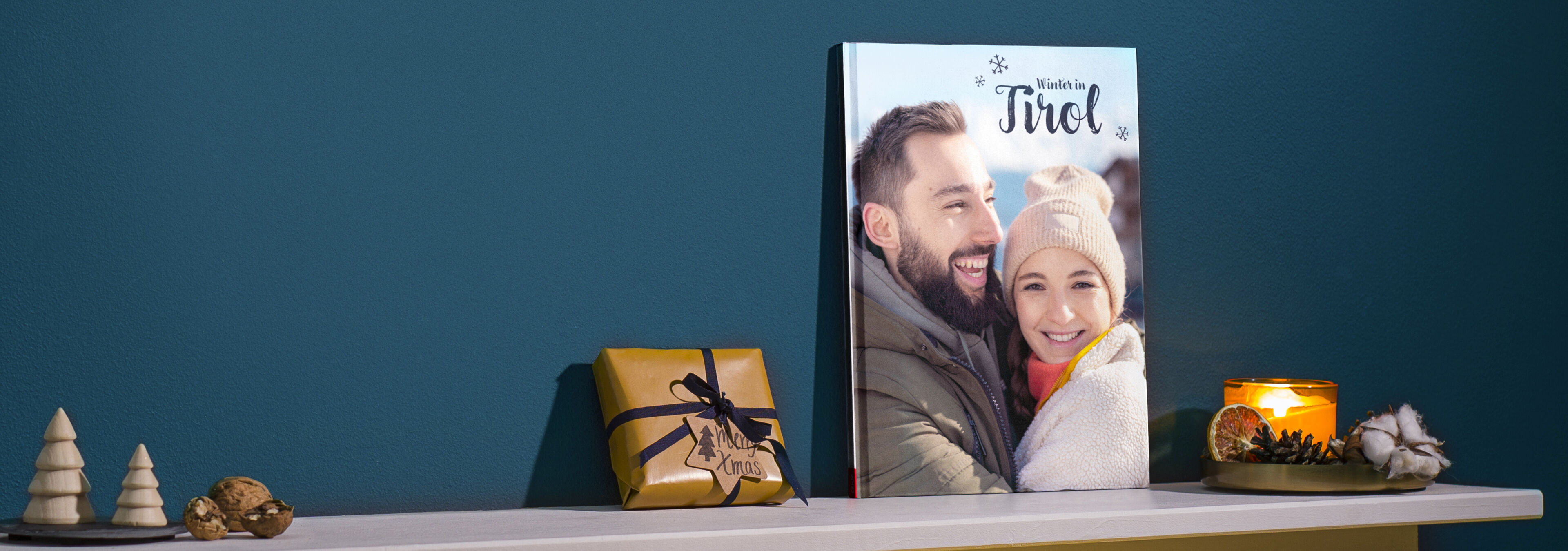 CEWE fotokniha na stole, ozdobená darčekmi a sviečkami.