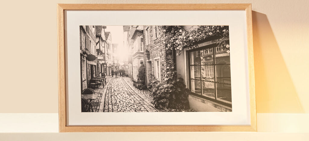 Čiernobiela fotografia dláždenej ulice v meste v drevenom ráme.