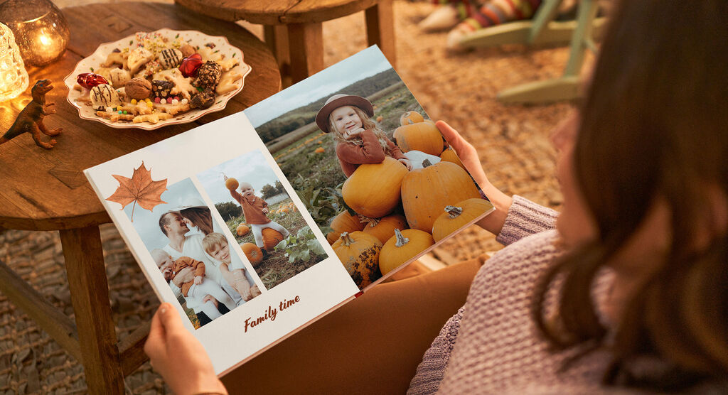 Osoba drží fotoknihu o rodinnom čase s tekvicami a fotografiami.