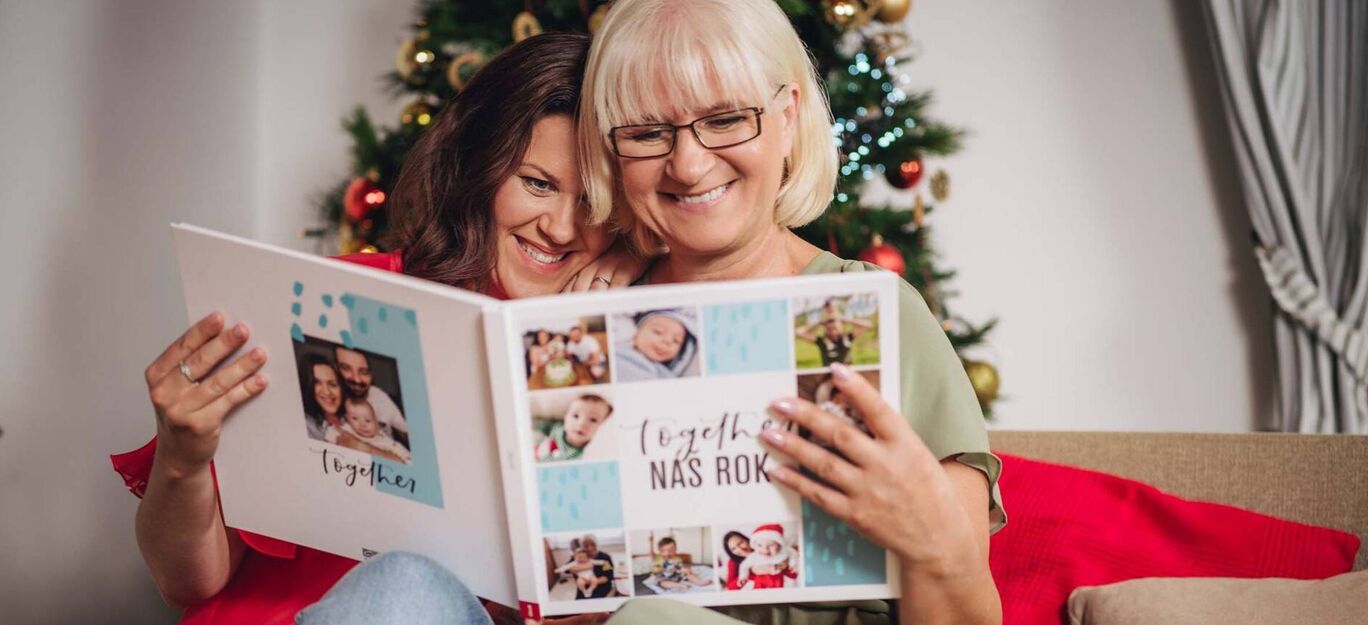 Dve osoby listujú v CEWE FOTOKNIHE s rodinnými fotografiami.
