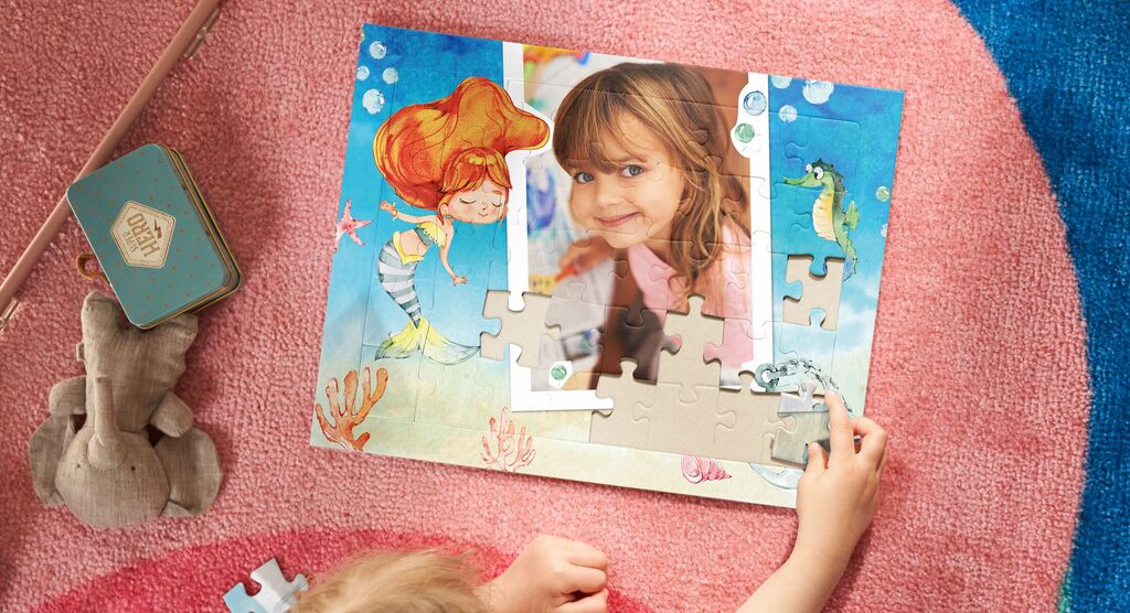 Dieťa skladá puzzle s podmorským motívom, obklopené farebnými detailmi.