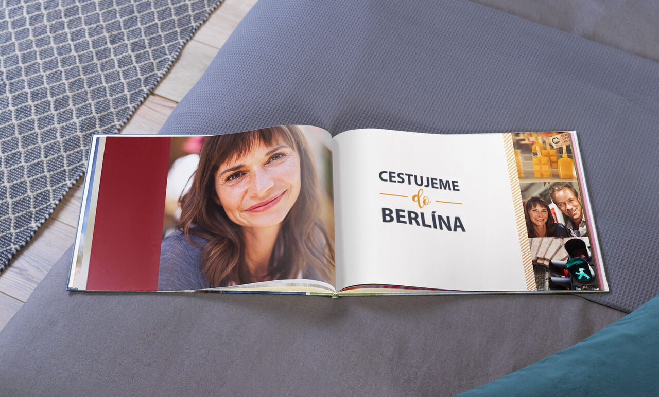 Otvorená CEWE FOTOKNIHA na pohovke s fotkami a názvom "Cestujeme Berlínom".