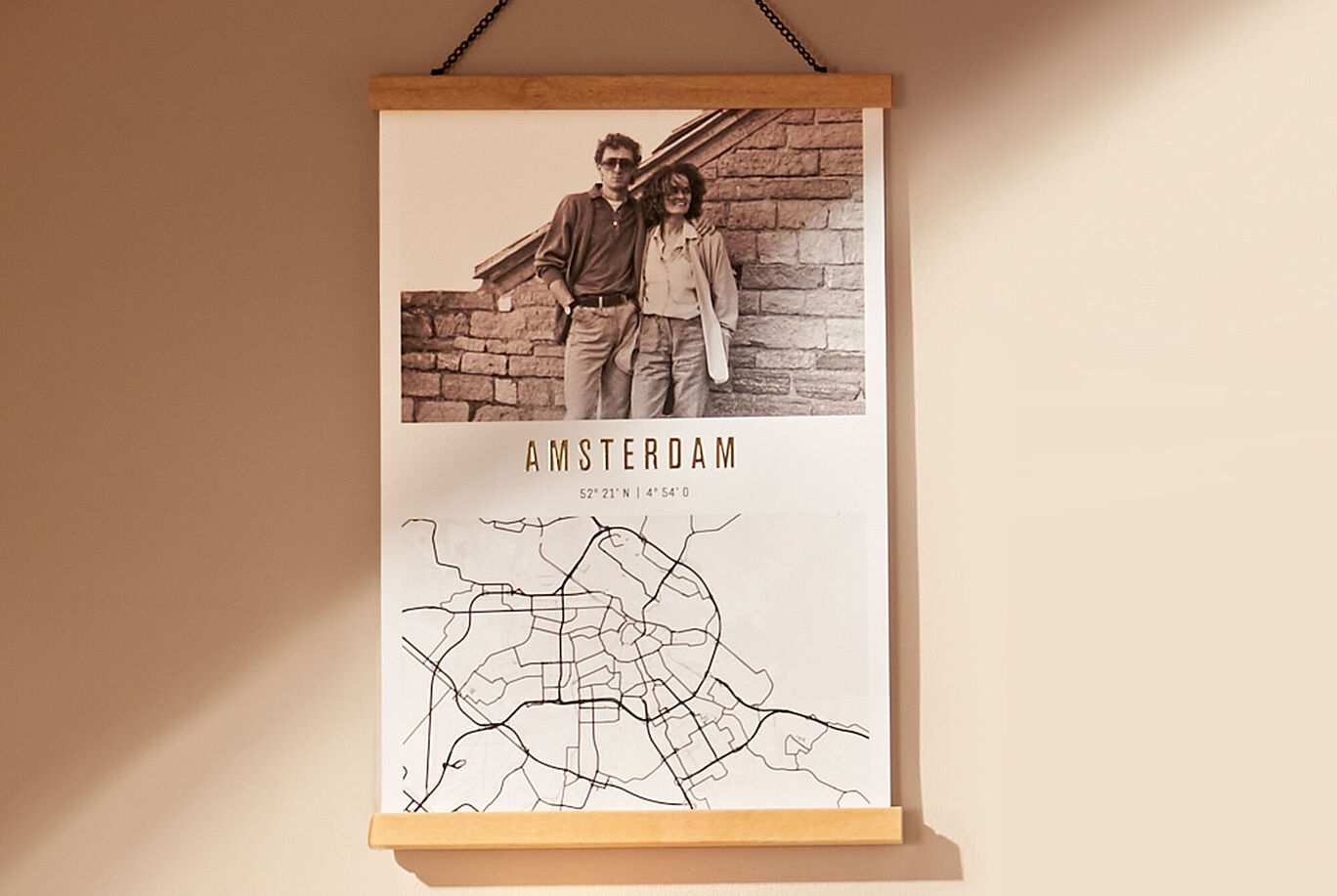 Obraz na stenu zobrazuje čiernobielu fotografiu páru pred tehlovou stenou s mapou Amsterdamu dole.