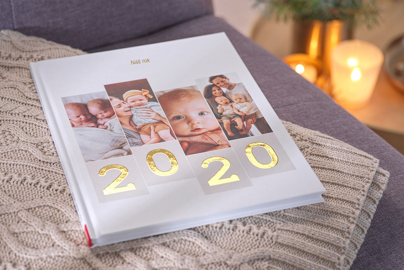 Láskavo navrhnutá CEWE FOTOKNIHA na pohovke, obklopená teplým svetlom a útulnou dekou. Na obálke je číslo 2020.