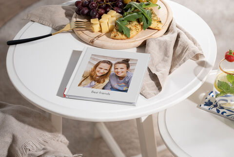 CEWE FOTOKNIHA na stole so syrovou misou a hroznom.