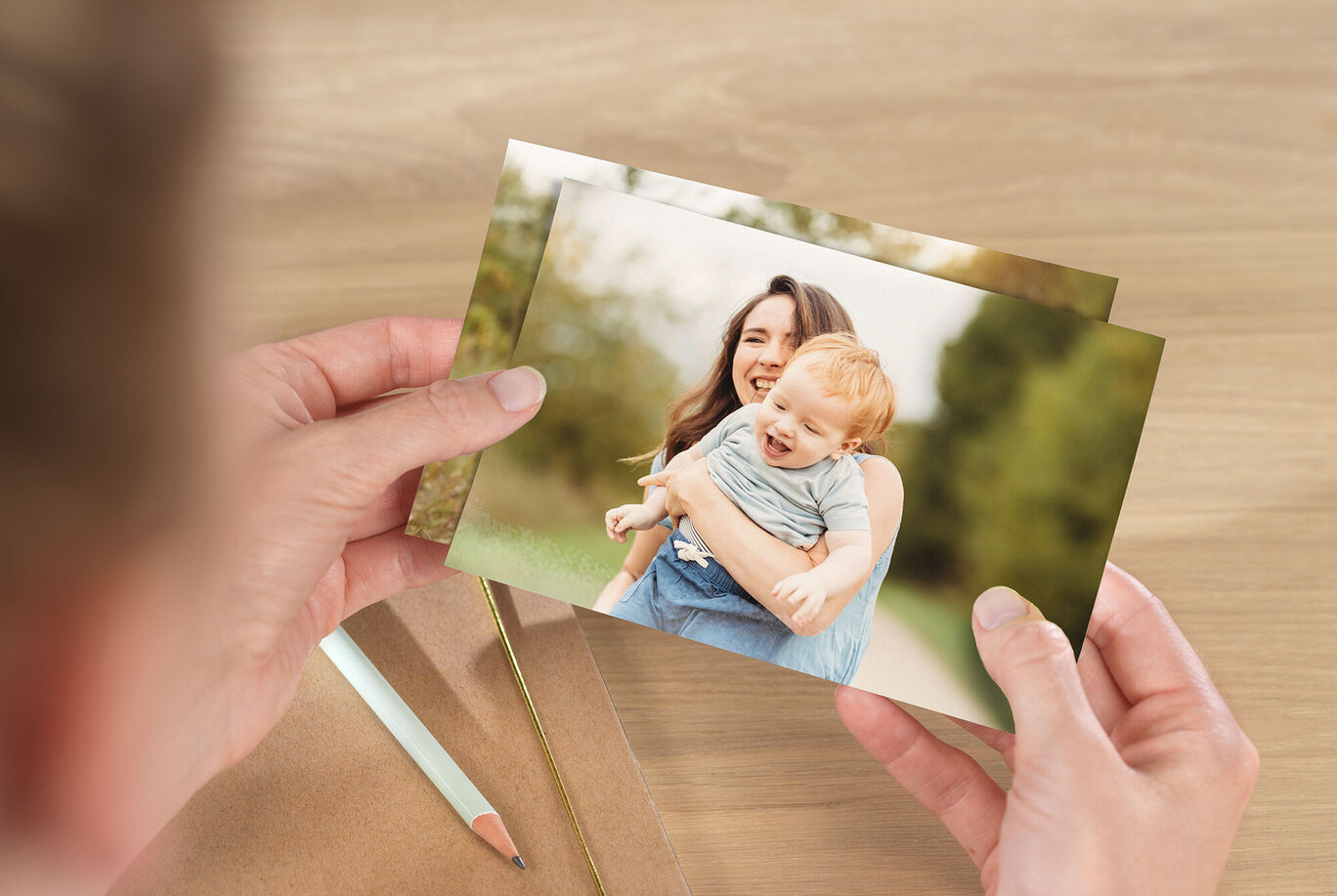 Osoba drží dve fotografie spomienok v rukách