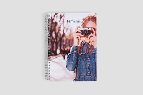 Kniha príležitostí s nápisom „Termíny“ a osobou držiacou fotoaparát.