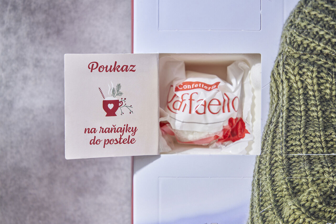 Darčeková poukážka na raňajky s nápisom "Poukaz na raňajky do postele" a sladkosťou vedľa nej.