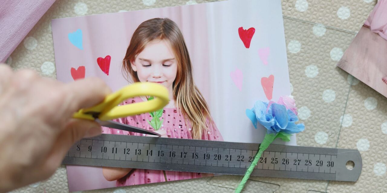 Osoba nožnicami strihá fotografiu so srdiečkami a kvetmi.