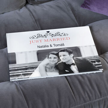 Otvorená fotokniha na sivej pohovke s názvom "Just Married".