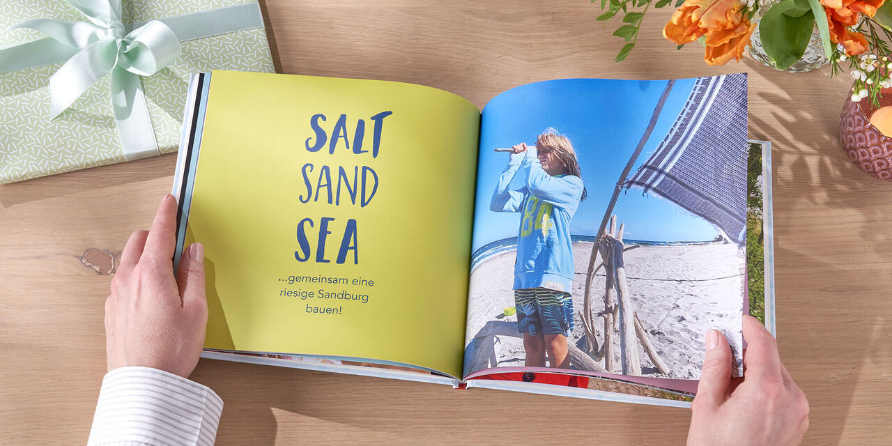 Niekto listuje otvorenou fotoknihou s názvom 'Salt Sand Sea' a ukazuje fotografiu dieťaťa na pláži.