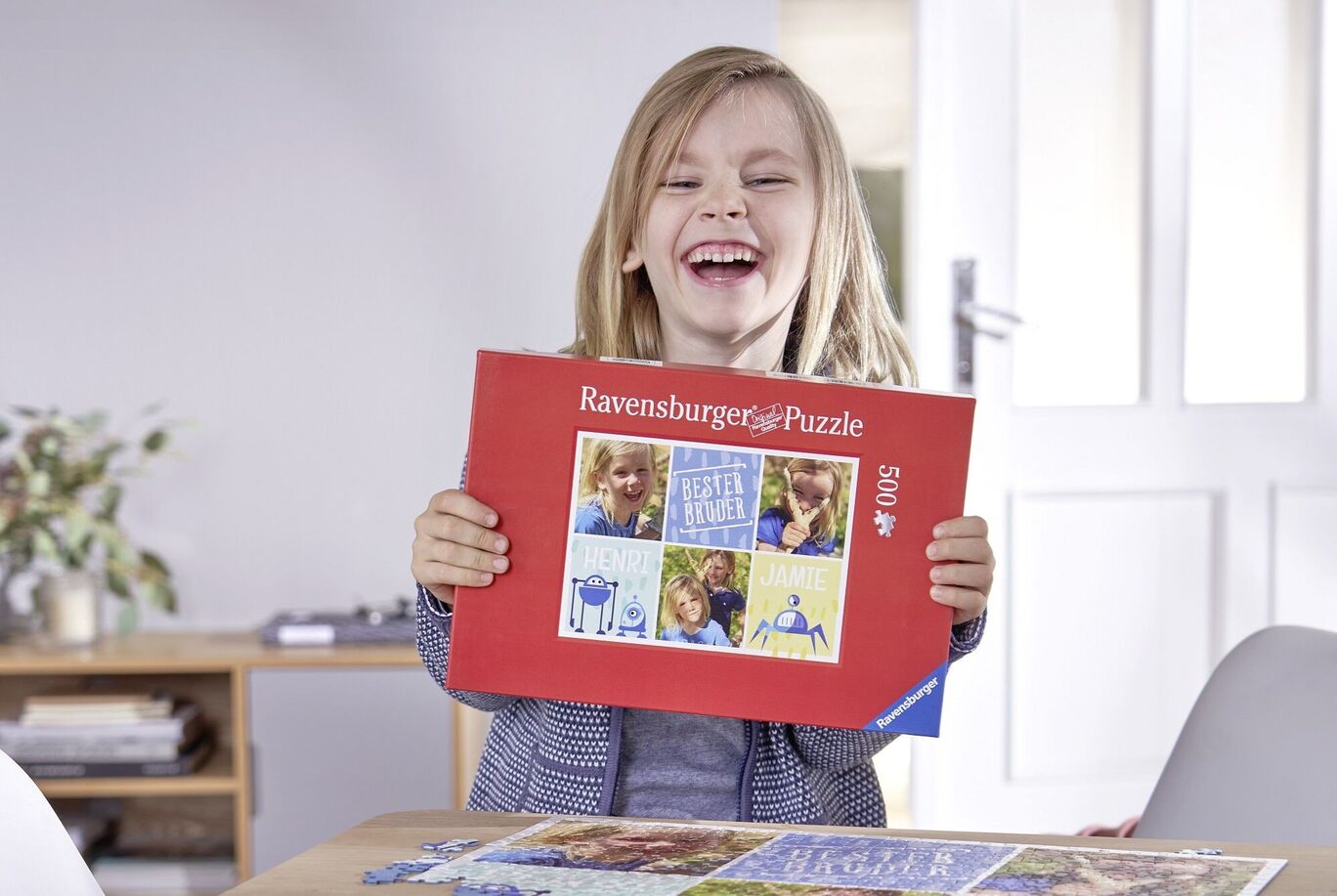 Šťastné dieťa drží puzzle Ravensburger a usmieva sa.
