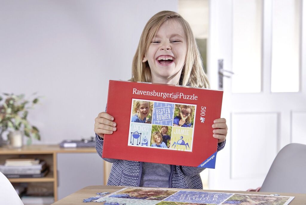 Šťastné dieťa drží puzzle Ravensburger a usmieva sa.