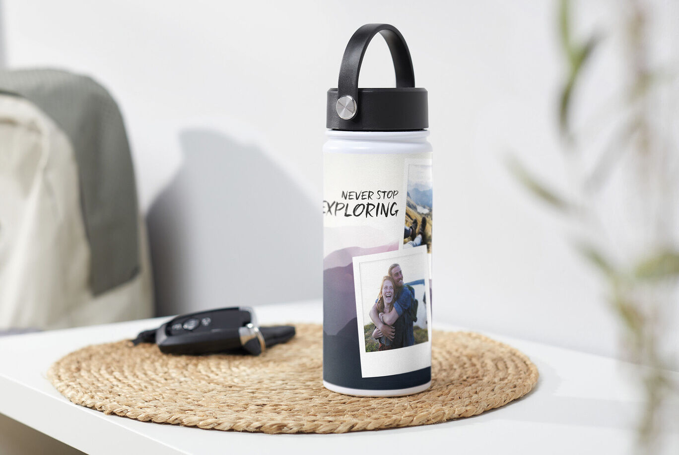 Personalizovaná fľaša s textom 'NEVER STOP EXPLORING' na stole, vedľa je kľúč od auta.