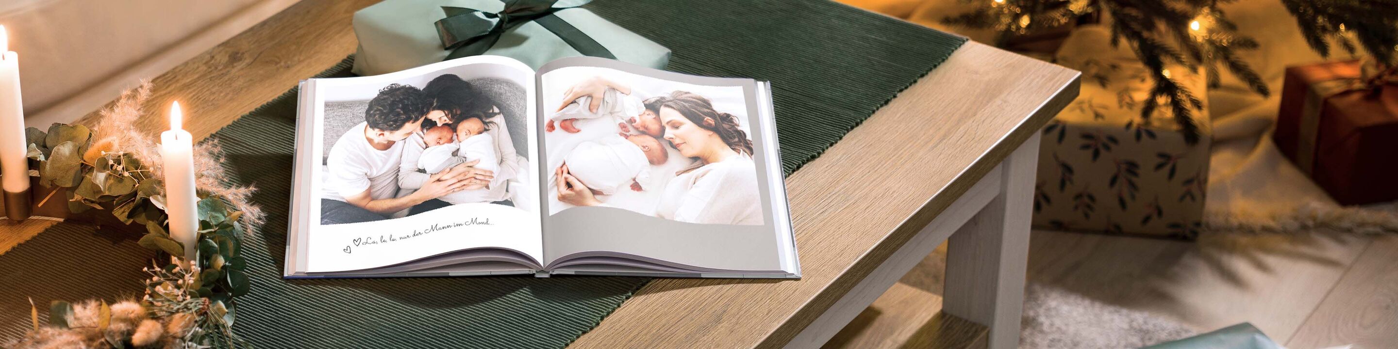 Otvorená CEWE FOTOKNIHA na stole, obklopená darčekmi a svetlom sviečky