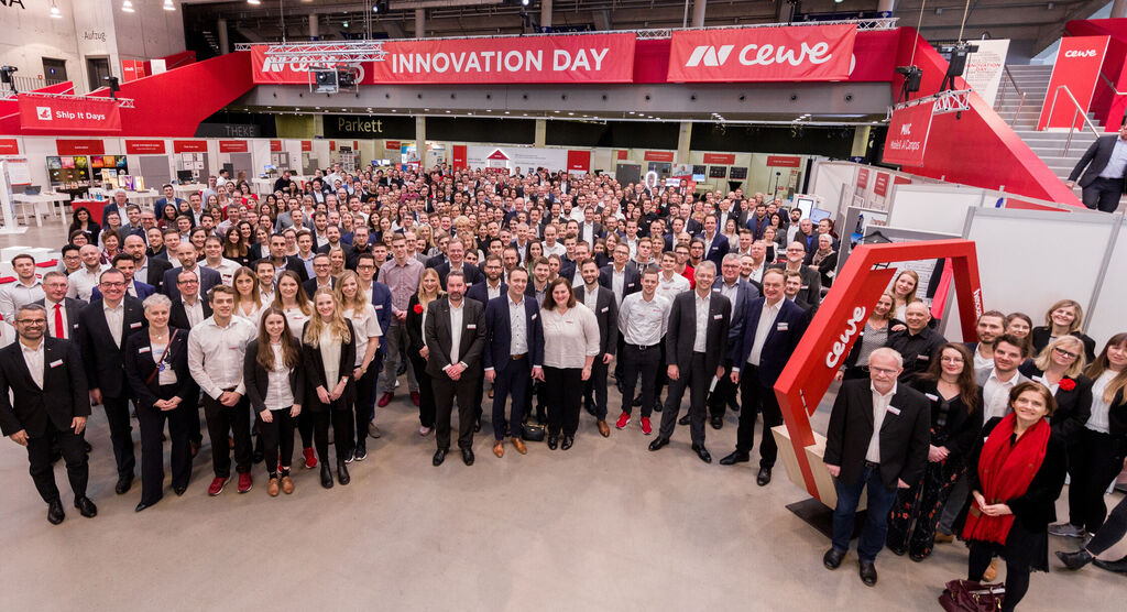 Skupinová fotografia ľudí na CEWE Innovation Day v hale, všetci sa usmievajú a prejavujú radosť z podujatia.