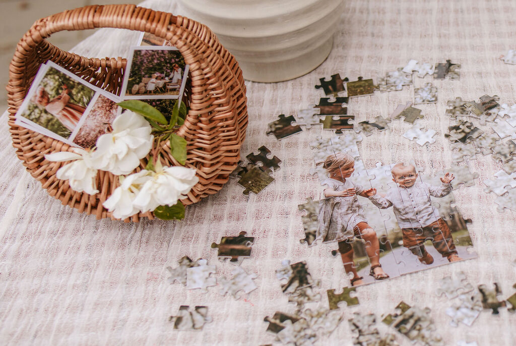 Kôš s fotografiami a dielikmi puzzle na stole.