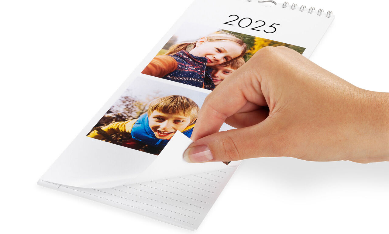 Ruka listuje CEWE fotokalendárom pre rok 2025 s fotkami šťastných momentov.