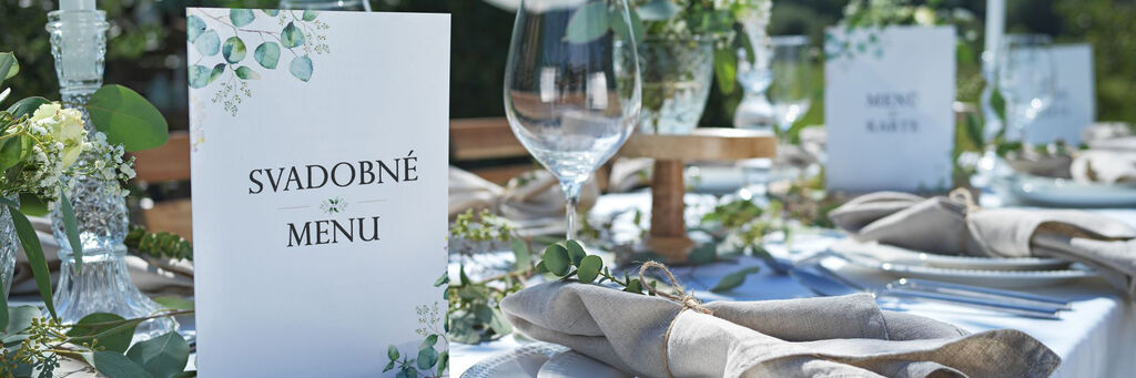 Elegantná dekorácia stola s menu kartami a čerstvými rastlinami.