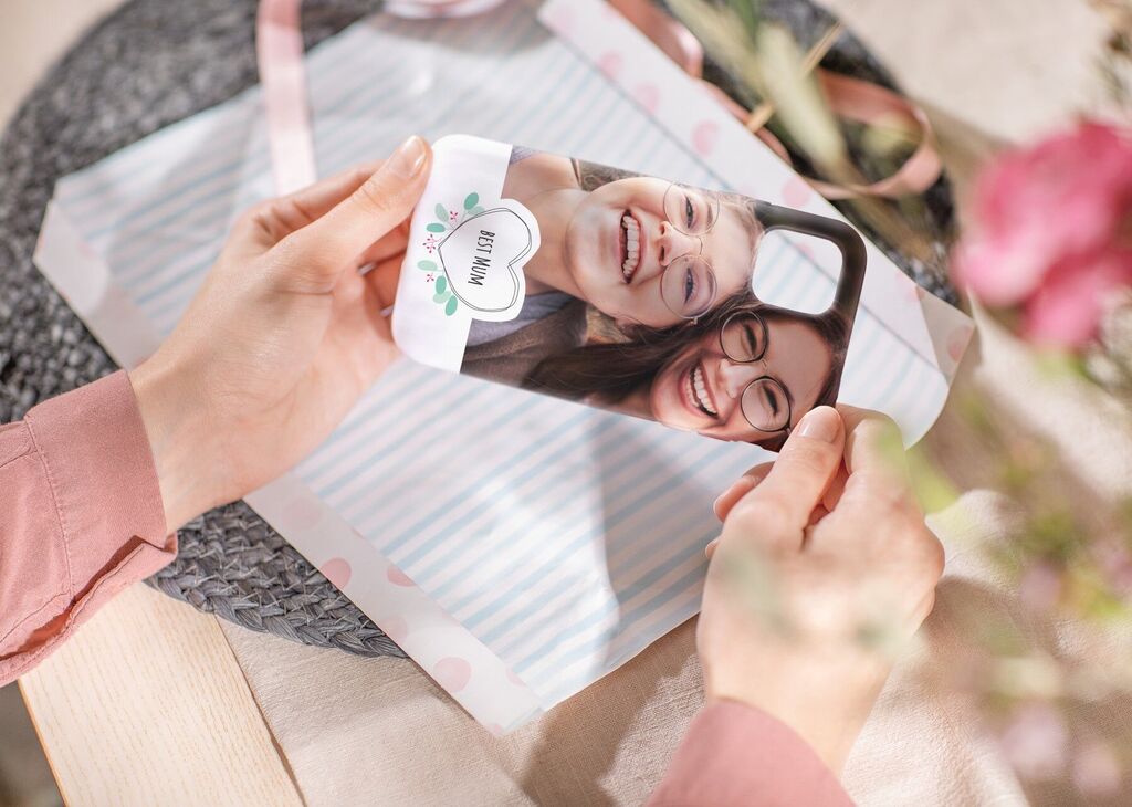 Osoba drží personalizovaný obal na mobil so fotografiou dvoch usmievavých žien.