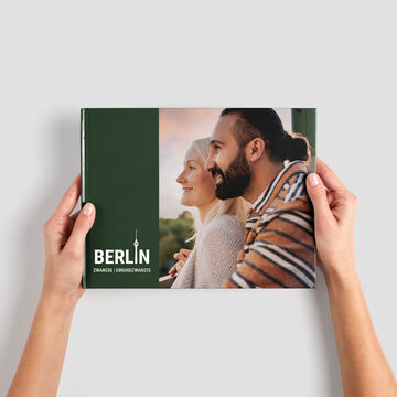 Pár drží CEWE FOTOKNIHU s berlínskymi spomienkami v rukách.