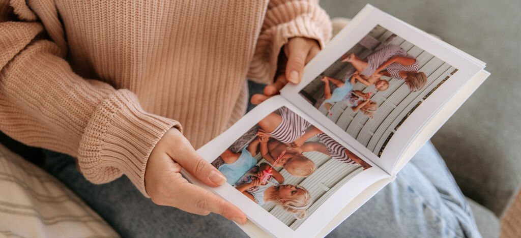 Osoba drží otvorenú fotoknihu s rodinnými fotografiami.