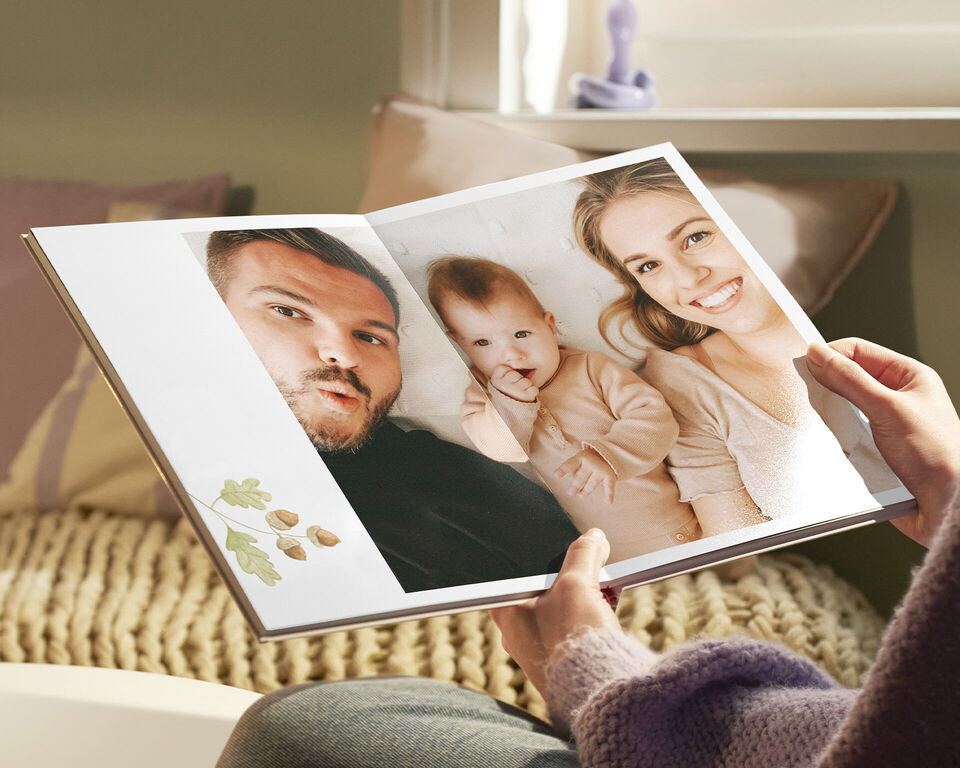 Osoba si nadšene prezerá otvorenú fotoknihu so spomienkami a kreatívnymi prvkami.