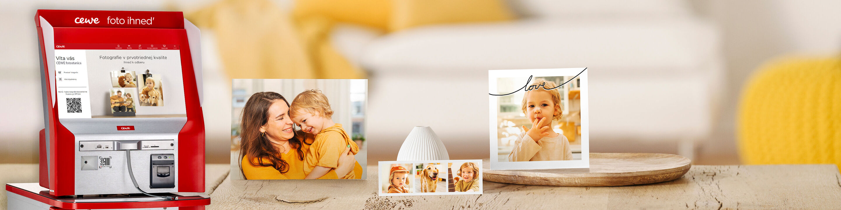 CEWE fotoautomat s obrazmi a rámami na stole.