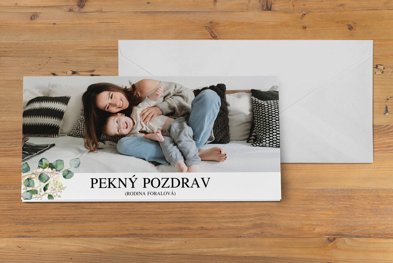 Láskavá pohľadnica s dieťaťom a osobou na pohovke s peknými vankúšmi na pozadí.