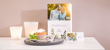 Láskyplne pripravená stolová dekorácia s pohľadnicou, šálkou so šľahačkou, cupcakeom a fotografiou.