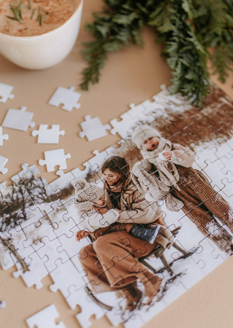 Žena a dieťa sedia spolu pri stole a skladajú puzzle. Okolo nich sú rozložené dieliky. Za nimi je vidiecka drevená scenéria.