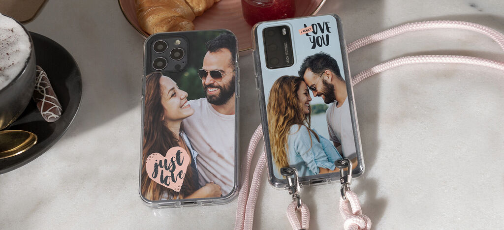 Dva personalizované obaly na mobily na stole s croissantmi a nápojmi.
