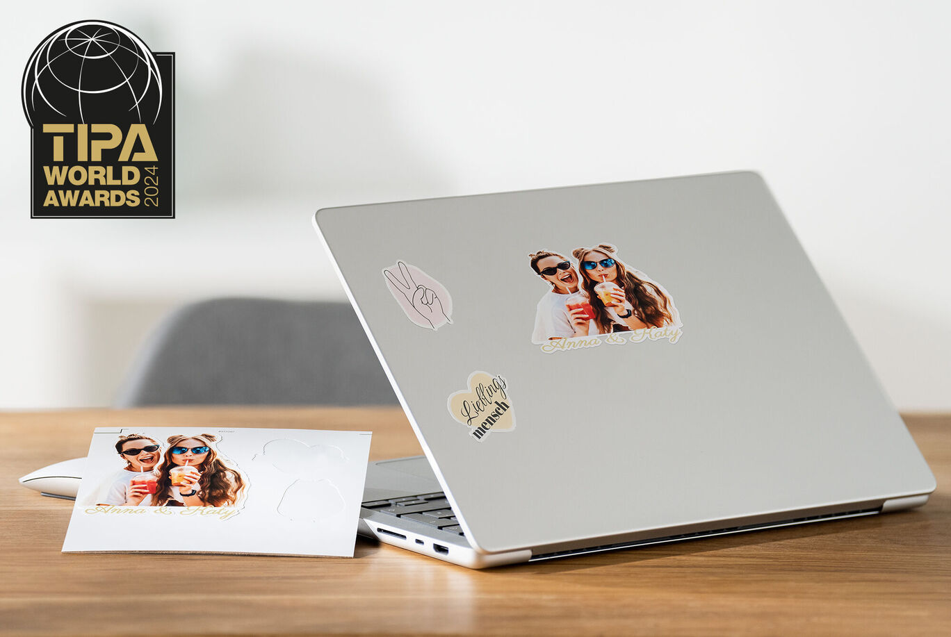 Laptop so samolepkami a pohľadnicou na stole