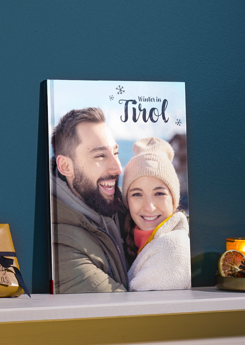 Dve osoby pózujú na obálke fotoknihy s názvom "Zima v Tirolsku"