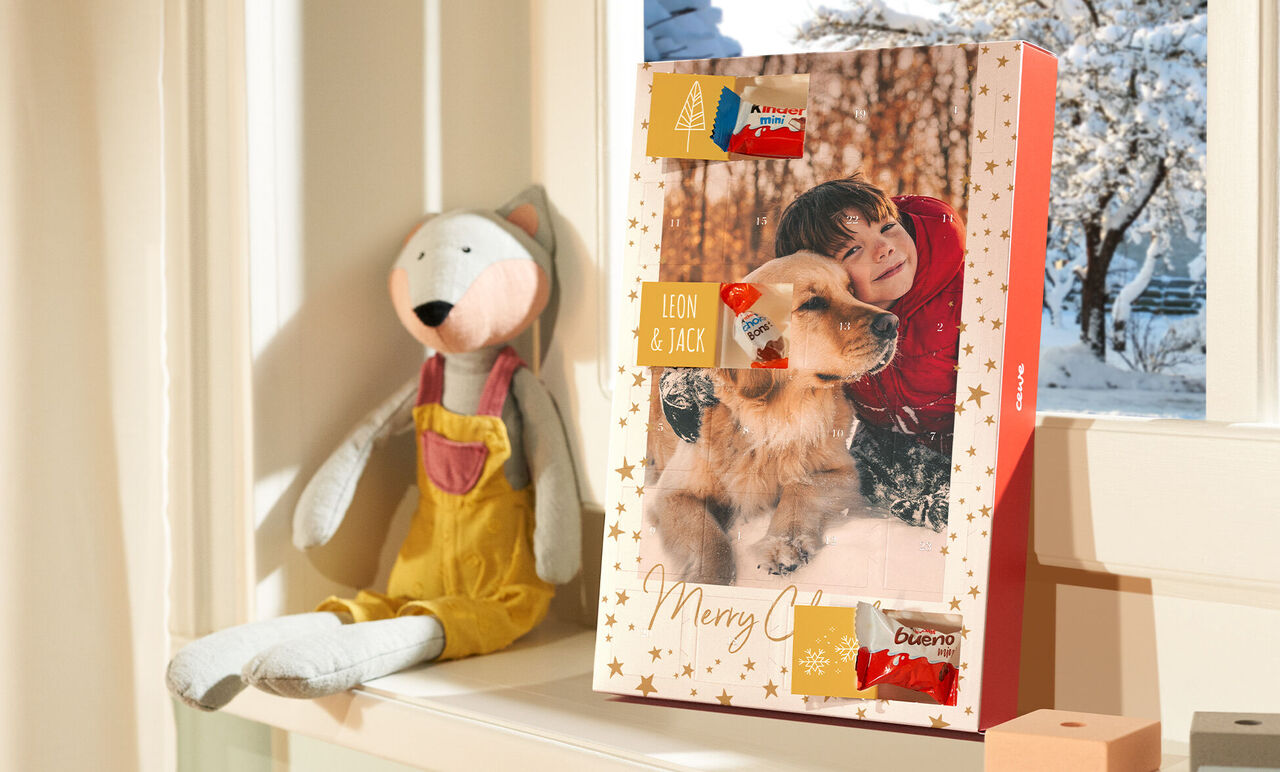 Adventný kalendár na okennom parapete, obklopený láskyplnou dekoráciou. Viditeľné sú rôzne dobroty.