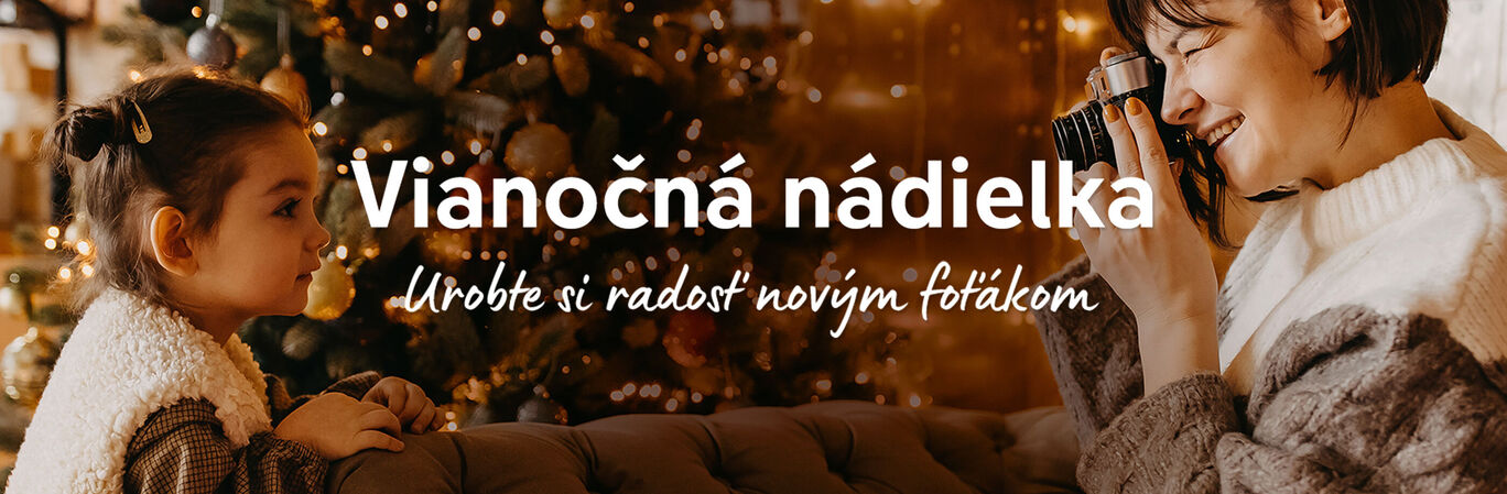 Dve osoby si užívajú Vianoce pred ozdobeným stromčekom