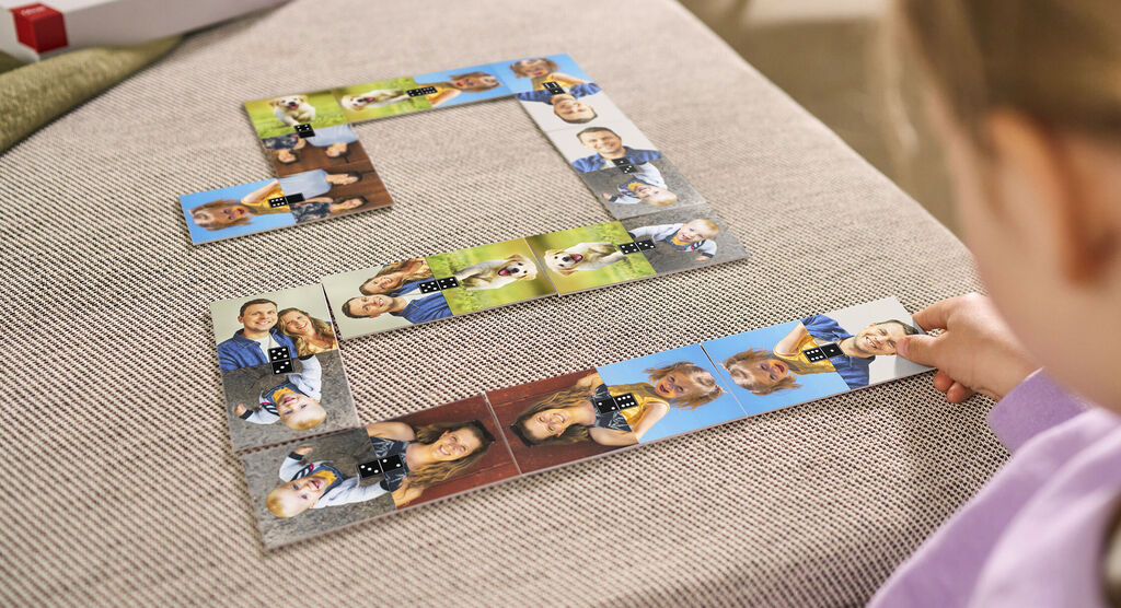 Dieťa sa hrá s personalizovaným fotopuzzle obsahujúcim obrázky šťastných momentov, usporiadaným na svetlej pohovke.