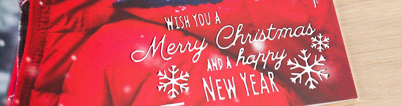 Sviatočná vianočná karta s textom 'Wish you a Merry Christmas and a happy New Year' na červenom pozadí so snehovými vločkami.