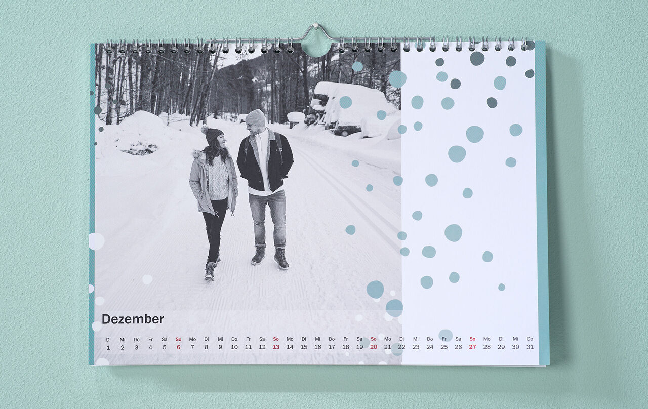 Pár kráča zasneženou krajinou. December má moderný štýl.