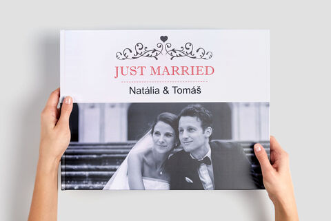 Dvaja ľudia držia CEWE fotoknihu s nápisom „Just Married“ a menami.