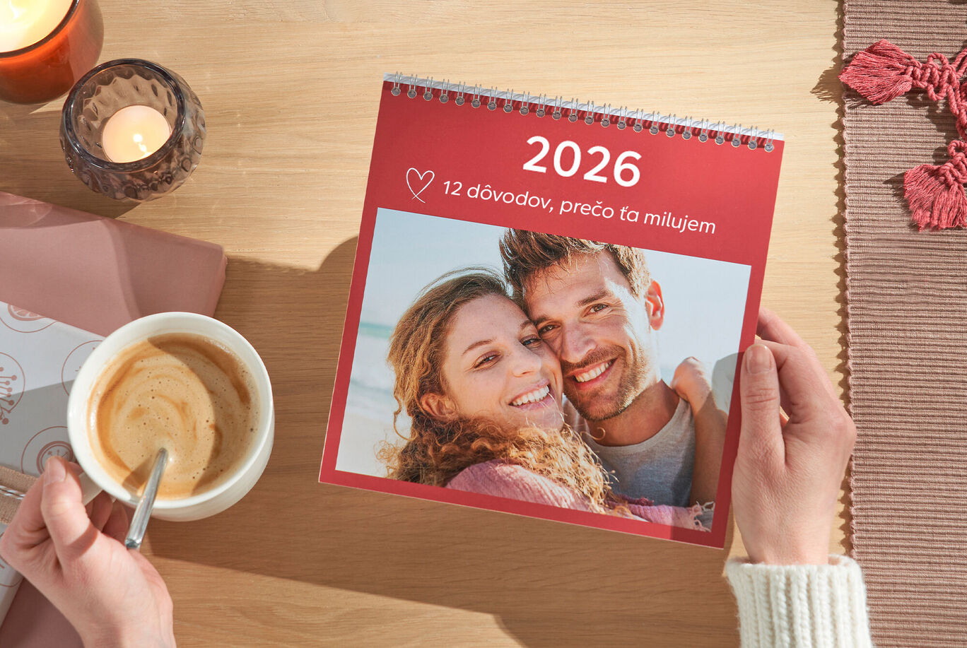 Osoba drží CEWE fotokalendár s romantickým obrázkom v ruke.